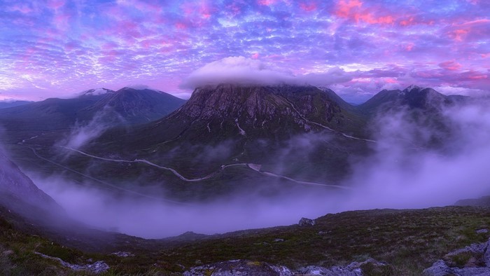 Purple and pink sky over Scottish mountains with fog