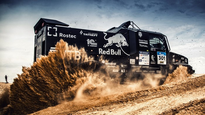Kamaz truck racing through desert with Red Bull sponsorship