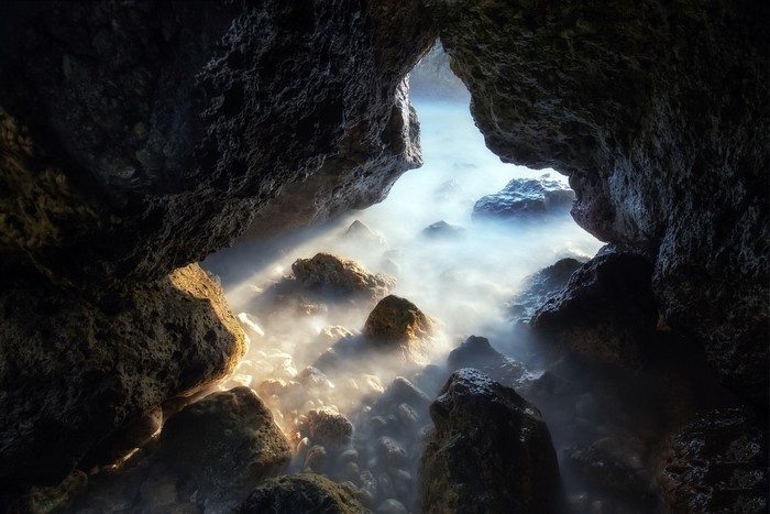 Sunlight streaming into a rocky sea cave