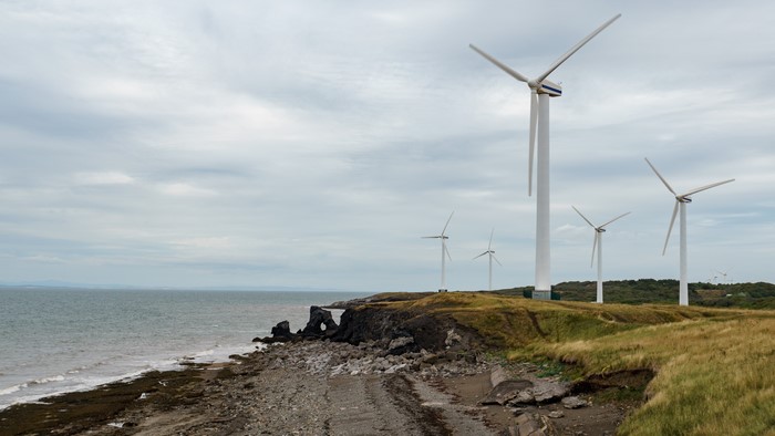Wind turbines on a rocky shore with the sea