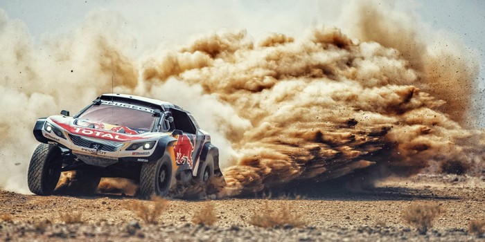 Peugeot rally car kicking up dust in the desert