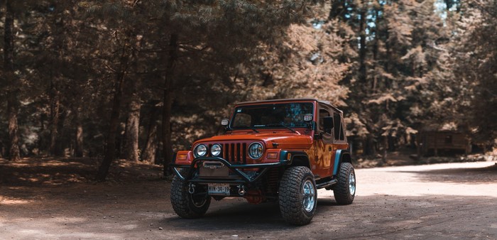 Orange Jeep Wrangler in a forest
