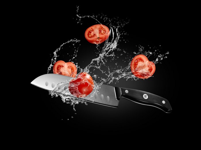 Knife slicing tomatoes with water splash