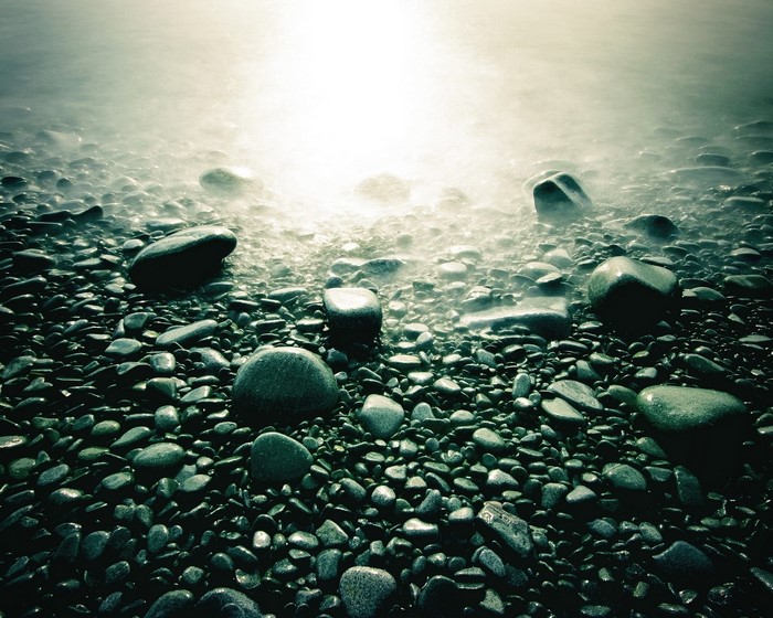 Pebble beach with glowing water at sunset