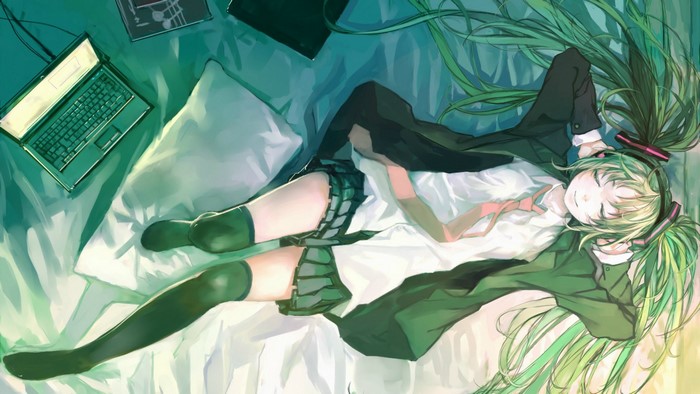 Hatsune Miku lying on a bed with a laptop