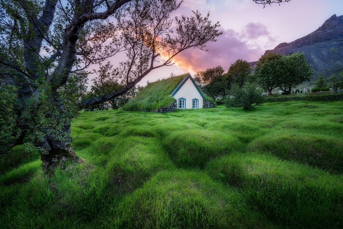 Grass-covered church in Iceland with a mountain backdrop