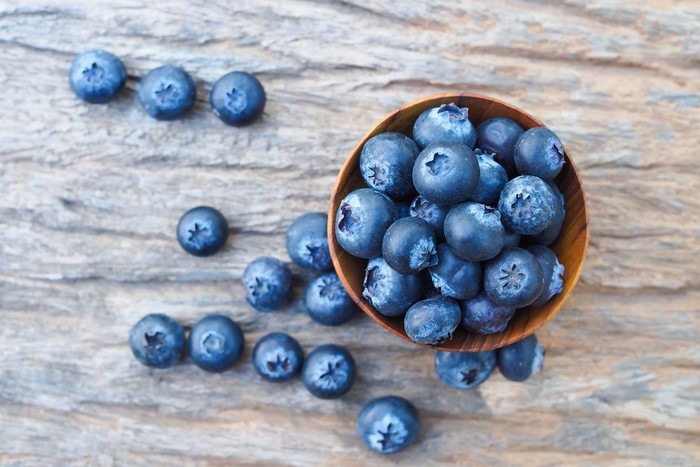 Blueberries in a wooden bowl on a wooden surface