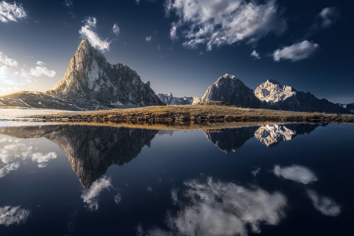 Mountain range reflected in a calm lake under a cloudy sky