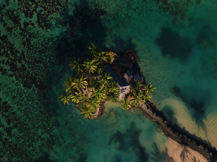 Aerial view of a small island with palm trees and huts in Fiji