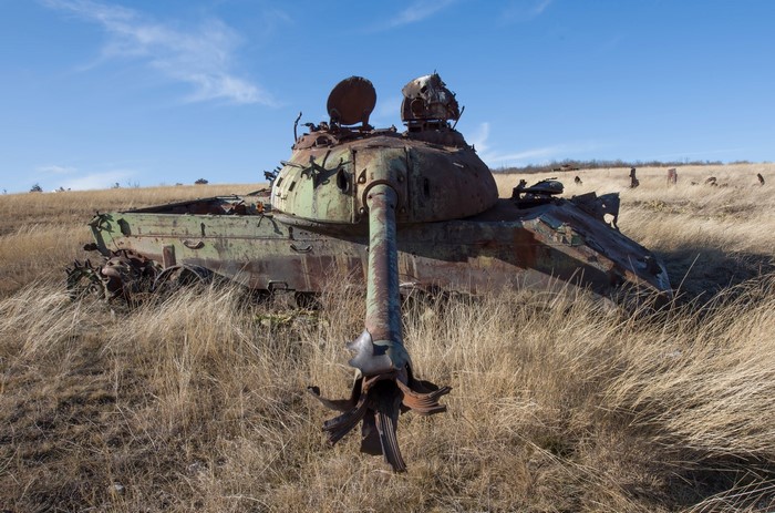 Wrecked military tank in a dry grassy field