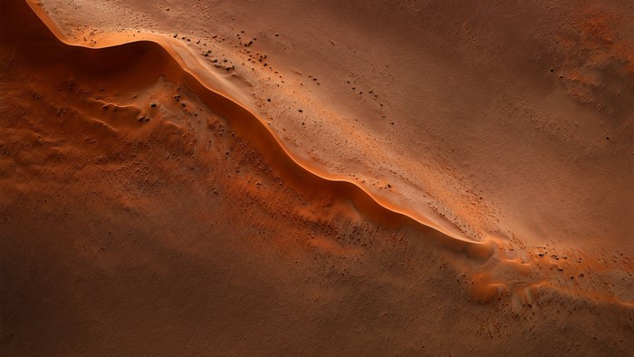 Aerial view of desert sand dunes with rocks