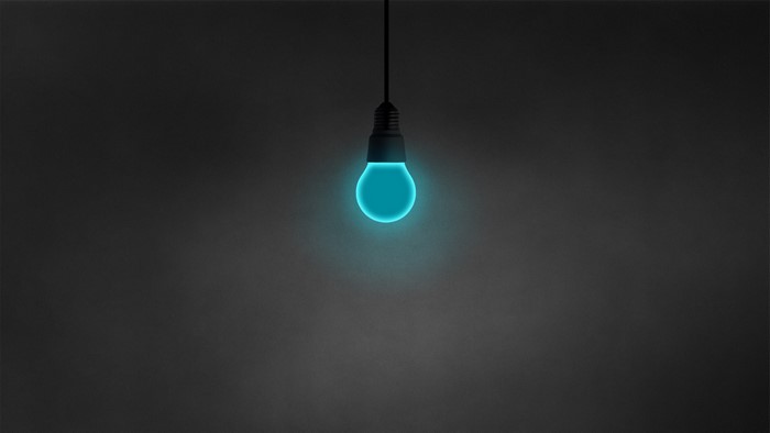 Cyan light bulb on dark background