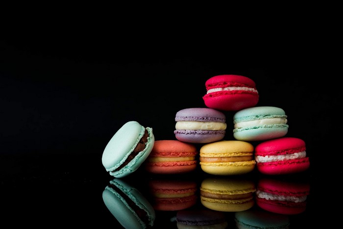 Colorful macarons stacked on a black background