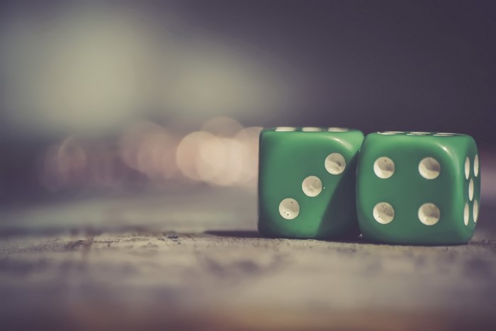 Two green dice on a wooden surface