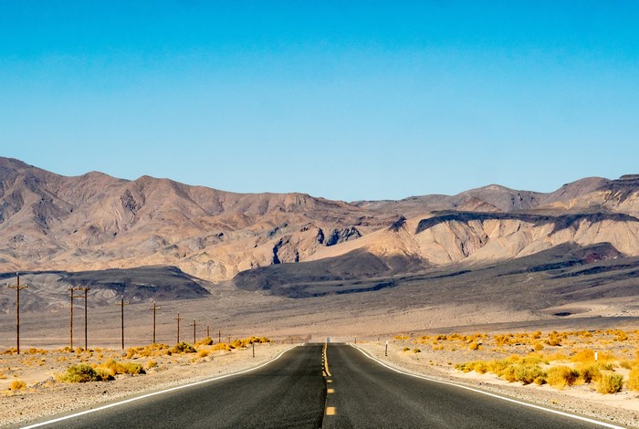 Asphalt road through desert landscape with mountains