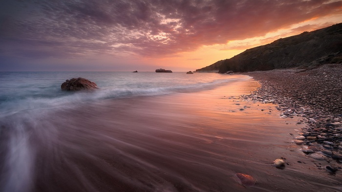 Sunset over a rocky beach with waves