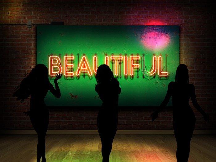 Silhouettes of women in front of a neon "BEAUTIFUL" sign