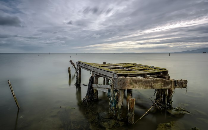 Abandoned pier on a calm sea under an overcast sky