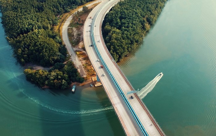 Aerial view of a bridge over water with trees and cars