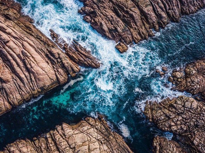 Aerial view of ocean waves crashing on rocky coastline