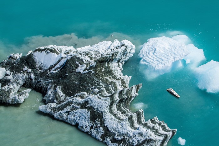 Boat sailing near icebergs in turquoise water