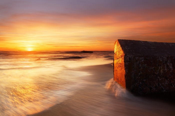 Sunset over the sea with a rock formation on the coast of France