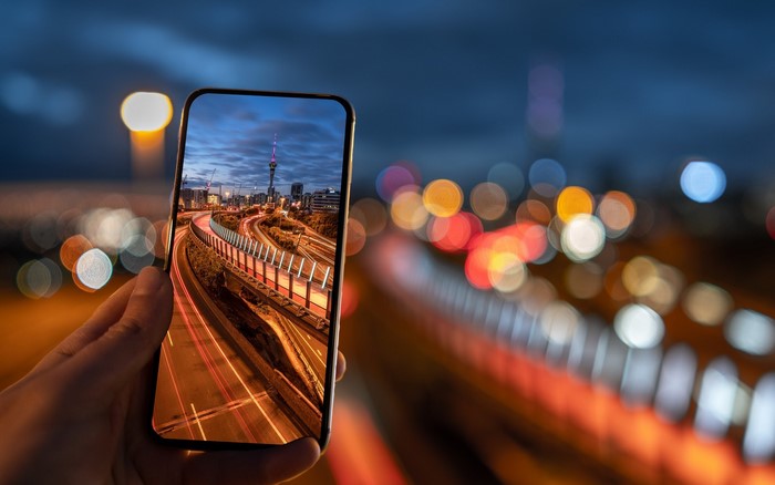 Smartphone displaying Auckland cityscape at night