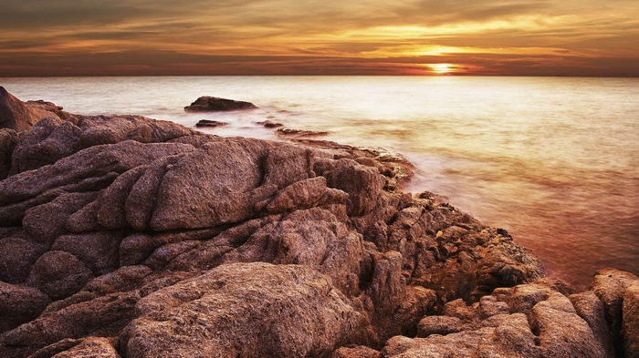Rocky coastline at sunset with calm ocean