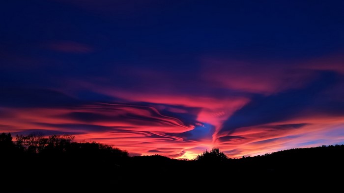 Dramatic sunset with colorful clouds over silhouetted hills