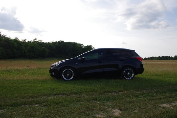 Black Kia Ceed station wagon in a field