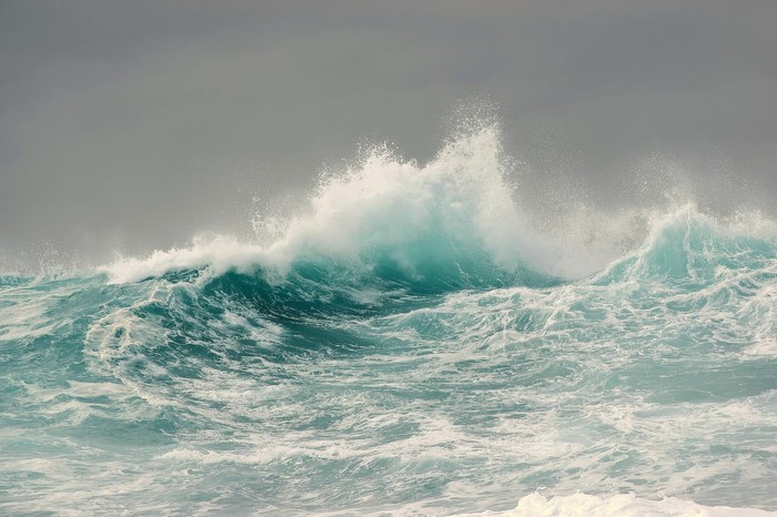 Turquoise ocean waves crashing under an overcast sky