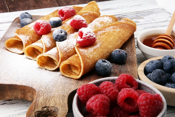Rolled crepes with raspberries, blueberries, and honey