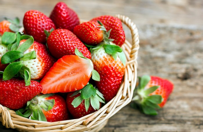 Basket of fresh strawberries on a wooden surface