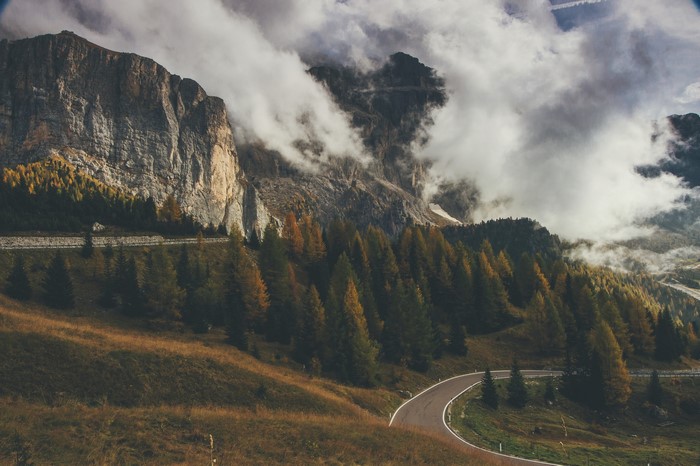 Mountain road winding through autumn trees with clouds