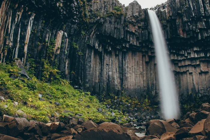 Waterfall cascading over basalt columns in a rocky landscape