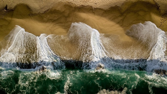 Aerial view of waves crashing on a sandy beach