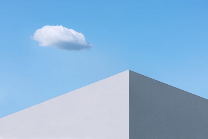 Minimalist architecture with a single cloud in a blue sky