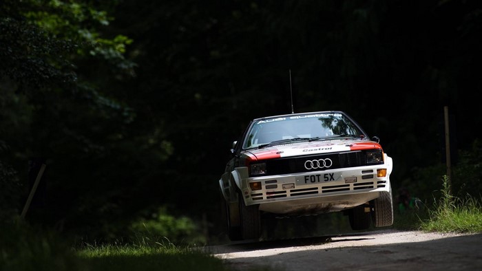 Audi Quattro rally car driving on a dirt road