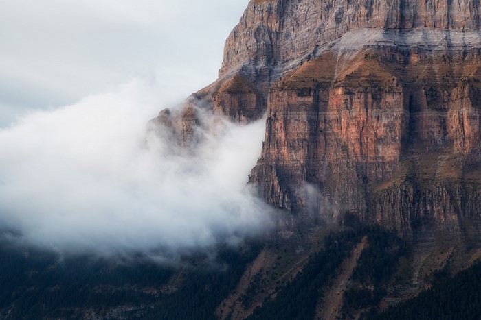 Mountain cliff face partially obscured by clouds