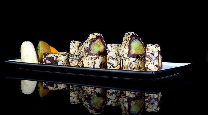 Chocolate-covered fruit rolls with almonds on a plate