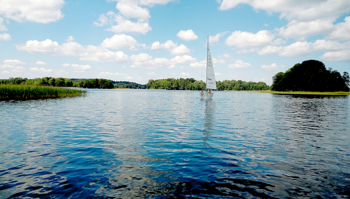 Sailboat on a lake with trees and clouds