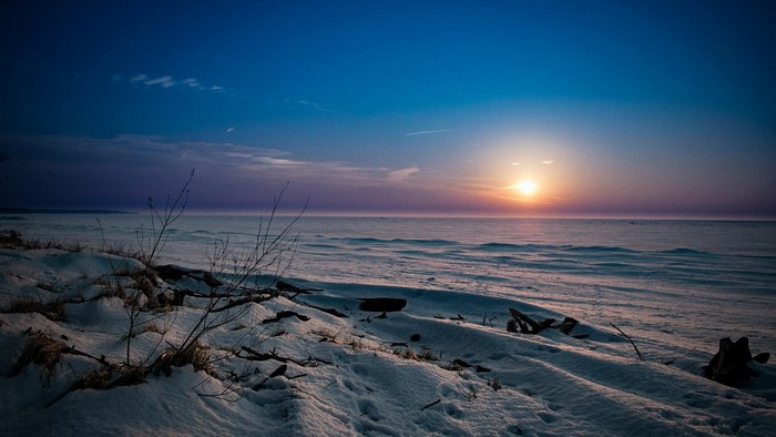 Snowy Shoreline at Sunset Over Frozen Lake