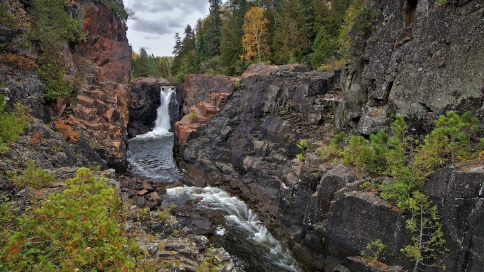 Waterfall cascading through rocky gorge with autumn trees