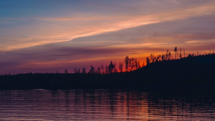 Sunset over a lake with a forest silhouette