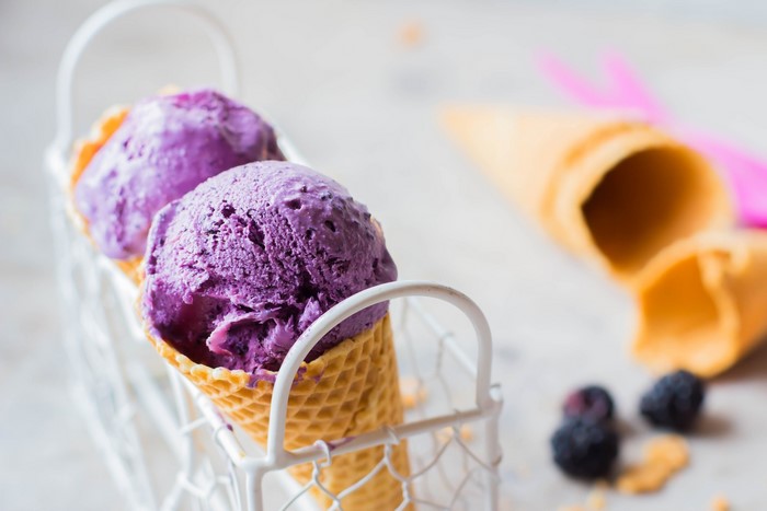 Purple ice cream cones in a basket with berries