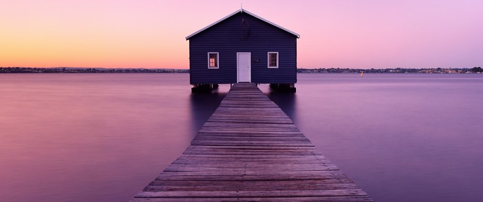 Dark blue boathouse on a pier at sunset