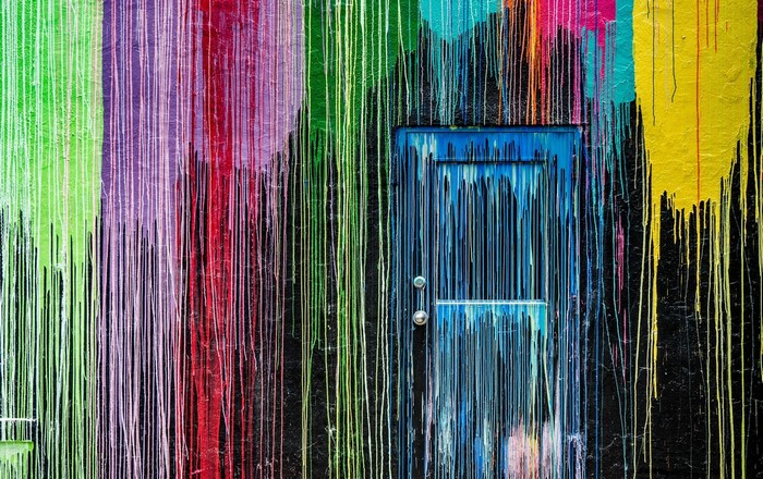 Colorful dripping paint on a wall with a blue door