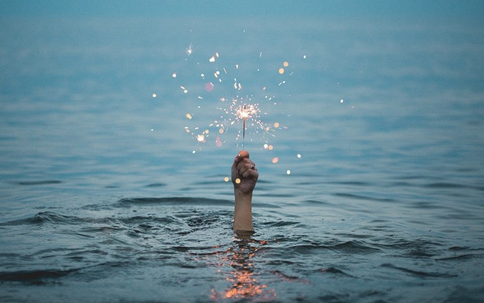 Hand holding a sparkler in the water