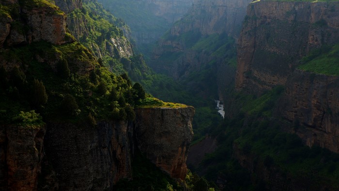 Sunlight illuminates a deep canyon with a river below
