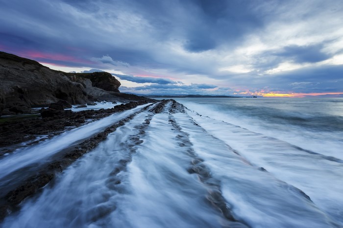 Ocean waves crashing on rocky shore at sunset